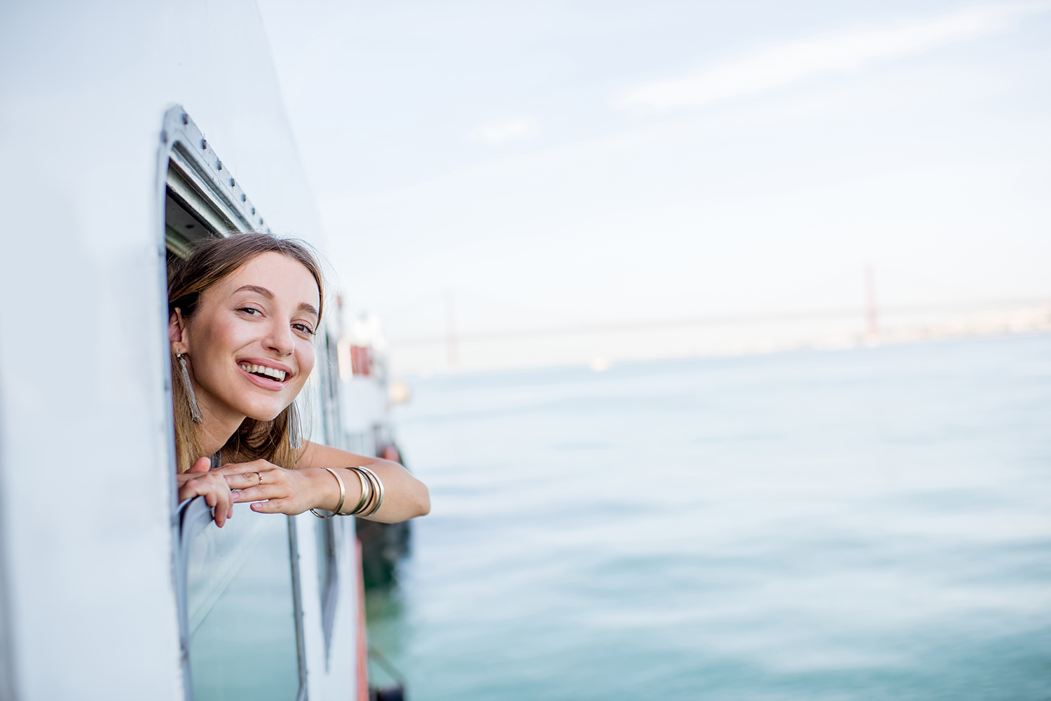 A smiling traveller on a ferry represents the beginning of a responsible travel journey, reminding us that everyday habits at home shape the environment we explore.